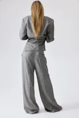 Pantalón de vestir gris claro, de tiro alto, con bolsillos laterales y traseros. Piernas amplias con pliegues delanteros y traseros. Confeccionado en tejido liviano de mezcla de lino y viscosa.