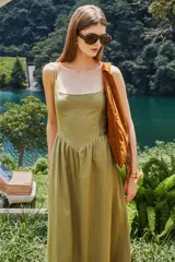 Vestido midi de lino y viscosa color beige claro, con escote cuadrado y breteles finos. Presenta un detalle de punto smock en la espalda y bolsillos laterales.