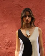 Collar con dije de nácar de forma irregular y orgánica, suspendido de un cordón fino en tono neutro.