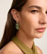 Aros colgantes dorados con piedras verdes.