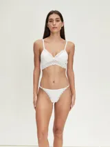 Conjunto de ropa interior blanco, compuesto por un bralette con encaje y una tanga con encaje.