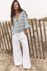Pantalón de jean blanco, de tiro medio, corte wide leg y pinzas delanteras.