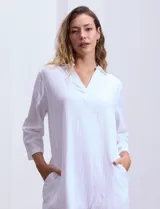 Vestido corto blanco de algodón con cuello con solapa y escote en V. Tiene mangas tres cuartos regulables con presilla y botón, bolsillos laterales y forro interno a tono.