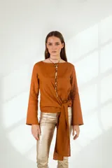 Blusa color ocre de lino con mangas largas acampanadas y nudo en la cintura.