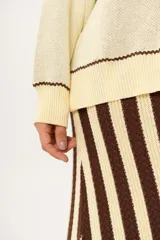 Sweater color manteca de tejido de punto con cuello redondo y ribete marrón. Presenta dos peces marrones tejidos en el frente con detalles bordados a mano.