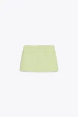 Falda pantalón corta color blanco, de tiro medio con bolsillos delanteros y cintura asimétrica. Cierre lateral con cremallera oculta.