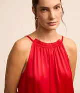 Vestido midi satinado color rojo, sin mangas, con cuello fruncido y cierre por lazo trasero.