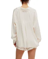 Camisa color crema de corte holgado, con cuello con solapa, cierre frontal con botones, bolsillo frontal y mangas largas con puños de encaje.