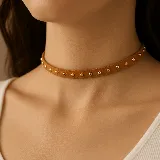 Gargantilla tipo choker color marrón de gamuza con tachas doradas.