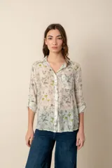 Camisa celeste con estampado de soles, lunas, flores y tortugas en tonos verdes, amarillos y naranjas.