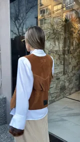 Chaleco marrón de cuero descarne con terminación en picos, tachas metálicas y flecos en la espalda.