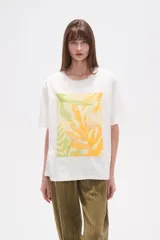 Remera blanca de manga corta y corte holgado, con un estampado central que simula una mano haciendo el signo de la paz, con detalles bordados y lentejuelas en tonos amarillo, verde claro y blanco.