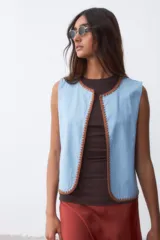 Chaleco celeste con terminaciones en crochet color marrón.