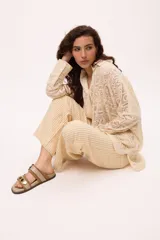 Sandalias bajas de cuero marrón con doble tira, hebilla ajustable y apliques de tachas metálicas.