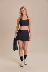 Pollera deportiva negra con short interno incorporado. Presenta un diseño con laterales redondeados y un bolsillo funcional en la cintura.