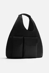 Bolso shopper negro de hombro fabricado en tejido técnico. Tiene un compartimento principal sin cierre, un bolsillo interior plano, un bolsillo interior con cierre de cremallera y dos bolsillos frontales con cierre magnético.