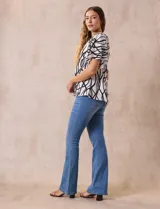 Blusa blanca estampada con líneas y lunares negros, de crepe marca Alex & Parker. Tiene cuello a la base, escote en V con botón y mangas cortas amplias.