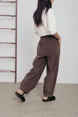 Pantalón de corte amplio color marrón, con cintura elastizada, detalle de botones en los laterales y cinturón incluido.