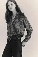 Camisa fluida con estampado reptil, escote redondo con apertura frontal y mangas largas terminadas en puño con botón.