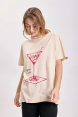 Remera color beige de corte holgado con estampado de una copa de martini en color rojo.