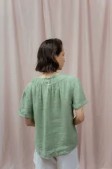 Blusa verde de lino con escote redondo fruncido y mangas cortas.