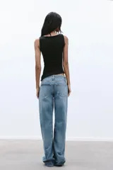 Musculosa negra con cuello barco, sin mangas, detalle de pliegues laterales y bajo asimétrico.