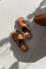 Chanclas de cuero color marrón claro, con suela plana y plantilla con logo de la marca.