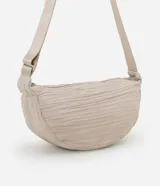 Bolso bandolera mediano color beige con textura drapeada y correa ajustable.