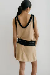 Minifalda color beige con detalle de volados negros en escote, cintura y sisas.