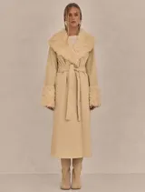 Abrigo trench maxi color beige con ribete de piel sintética en cuello y puños.
