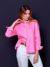 Camisa rosada de lino, de corte clásico, con cuello camisero, cierre frontal con botones y mangas largas con puños abotonados.