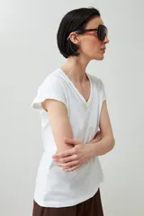 Remera color durazno con cuello en V y detalle de trenza en el escote.