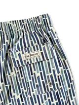 Short de baño blanco con estampado de hojas de palmera en tonos verde, rojo y amarillo.