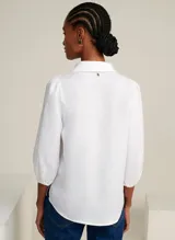 Camisa blanca de lino con cuello alto, escote en V, mangas 3/4 con volumen abullonado y puños elásticos.