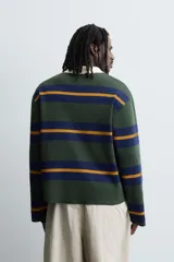 Polo de punto de corte relajado con diseño de rayas horizontales en tonos verde, azul y mostaza. Presenta cuello solapa en color crema a contraste y cierre frontal con tres botones.