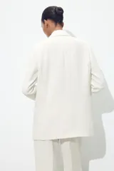 Blazer fucsia de cuello solapa y manga larga con hombreras. Detalle de tejido efecto arrugado. Bolsillos delanteros de vivo. Cierre frontal con un botón.