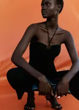 Mono largo negro de tejido fluido con anilla metálica en el cuello halter, tirantes finos y diseño recto.