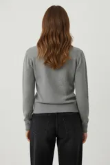 Sweater color crema con cuello redondo, manga larga y diseño de pequeños puntos en relieve.