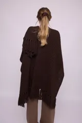 Ruana tejida en lana merino color negro con flecos en el borde inferior.
