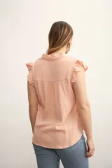Camisa color amarillo pálido con cuello mao, sin mangas, con volados en los hombros y en el frente.