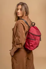 Mochila urbana de diseño compacto, color violeta/malva, con acabado ligeramente brillante. Presenta un compartimento principal con doble cierre superior y bolsillos laterales con cierre.