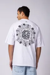 Remera oversize blanca de algodón con un pequeño estampado circular en el pecho que simula un cerebro o un diseño abstracto en espiral, en color negro.