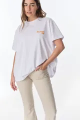 Remera blanca de algodón con cuello redondo y mangas cortas. Estampado pequeño en el pecho con la frase "The Flowers Club" en color naranja.