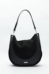 Bolso tipo hobo de cuero sintético negro con panel frontal de gamuza. Tiene correa de hombro ajustable y logo metálico plateado.