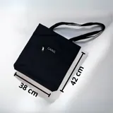 Bolso tipo tote bag negro con asas largas, bolsillo exterior con cierre y bordado con la palabra "GAINS." en blanco.