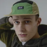 Gorra de cinco paneles con visera plana, color negro con secciones en verde y fucsia.