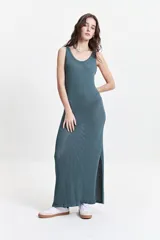 Vestido largo de punto color beige, con textura acanalada y escote redondo. De tiras finas y silueta al cuerpo, con tajo lateral.