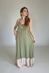 Vestido largo verde oliva con breteles finos y corte amplio. Tiene un ruedo en color beige.