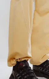 Pantalón de corte sastrero color amarillo claro, de tela suave tipo gamuza, con bolsillos laterales, cintura elástica ajustable y cierre con botón.
