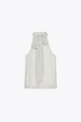 Top blanco con estampado de lunares negros, cuello halter con pañuelo y cierre con botón en la espalda.